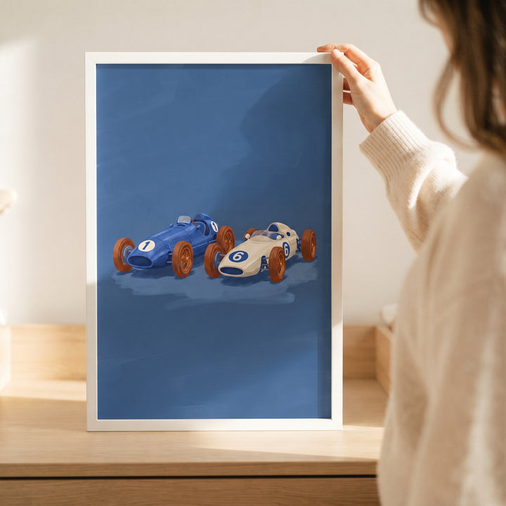 Number one blue car wall art and a white race car on a blue background, held in a white frame by a person.