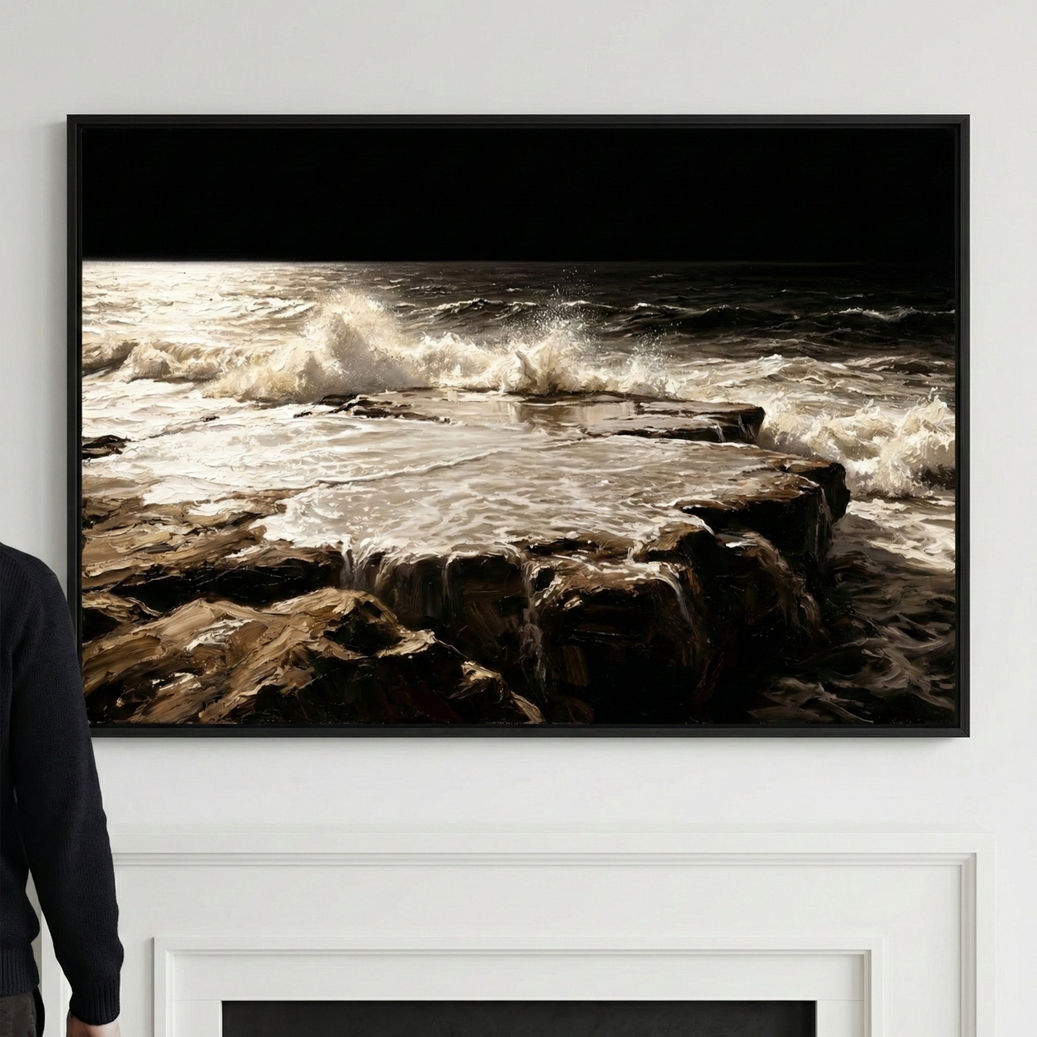A framed painting of powerful ocean waves crashing over a flat rocky ledge, with dark, dramatic water and foam under a black sky. The artwork is mounted above a white fireplace, creating a bold contrast in a minimal interior.