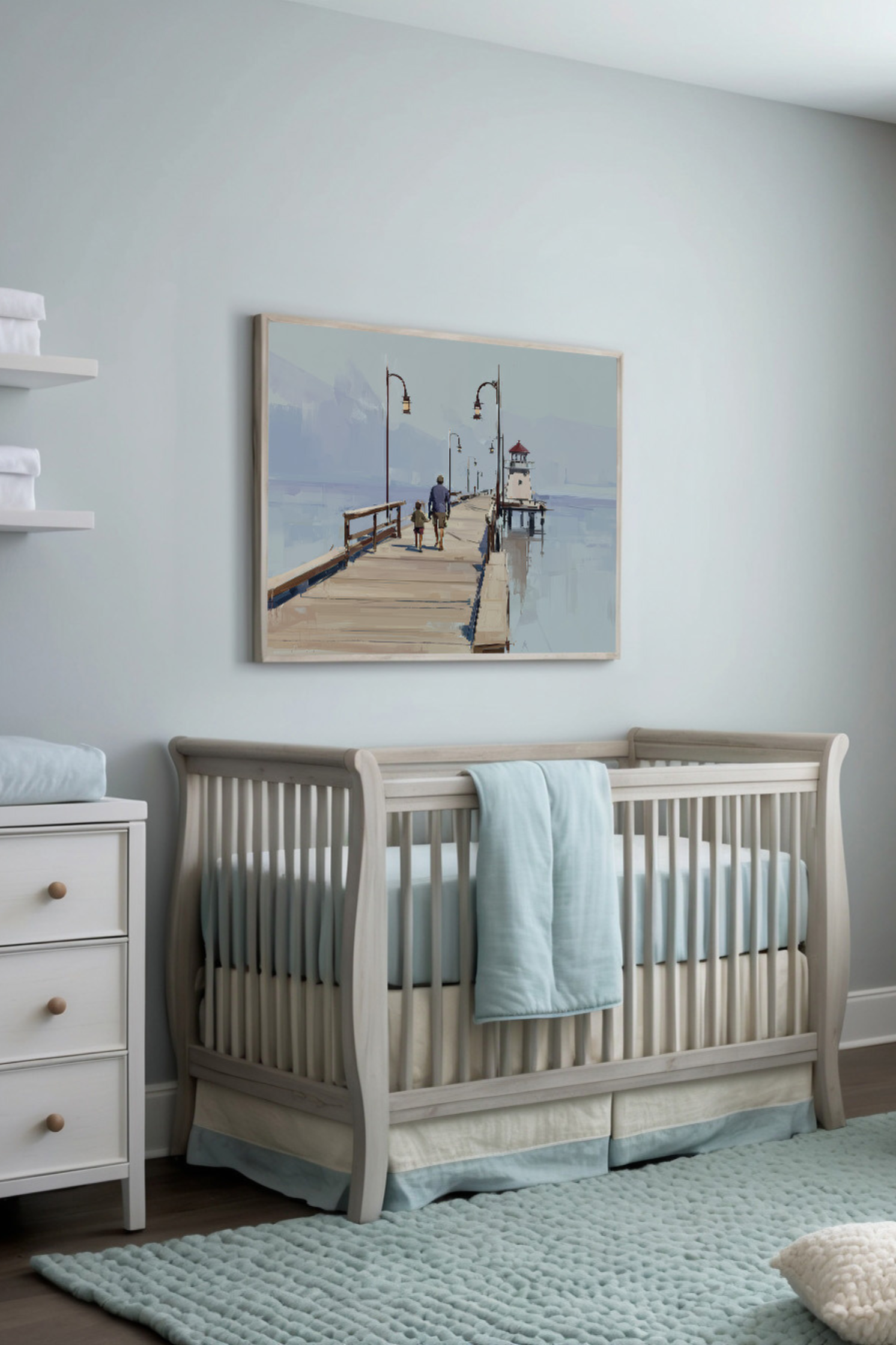 Calming nursery featuring soft blues, creams, and neutral furnishings, including a wooden crib dressed in gentle tones. A tranquil painting of two people walking along a wooden pier toward a lighthouse adds to the room's peaceful coastal charm.
