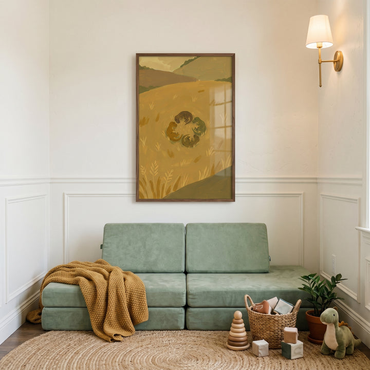 Ochre field baby t-rex wall art hangs above a sage green modular sofa with a mustard blanket, jute rug, and toys.