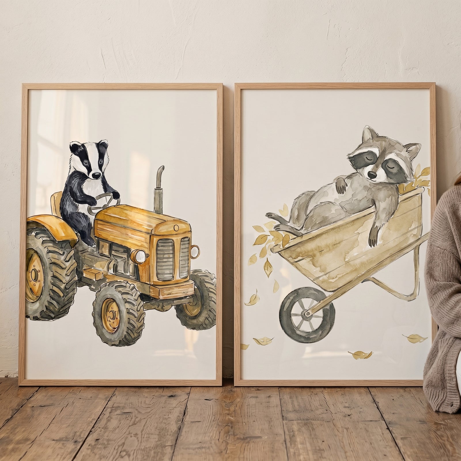 Ochre watercolor woodland animals wall art set of 2 with a badger on a tractor and a raccoon in a wheelbarrow.