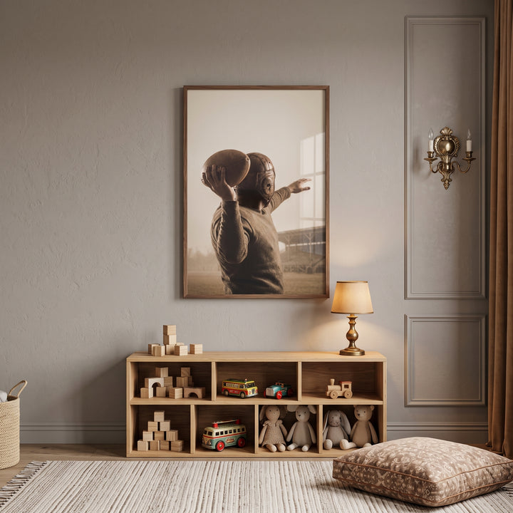 Old leather helmet quarterback sports wall art hangs above a wooden toy shelf, lamp, and floor pillow in a neutral room.