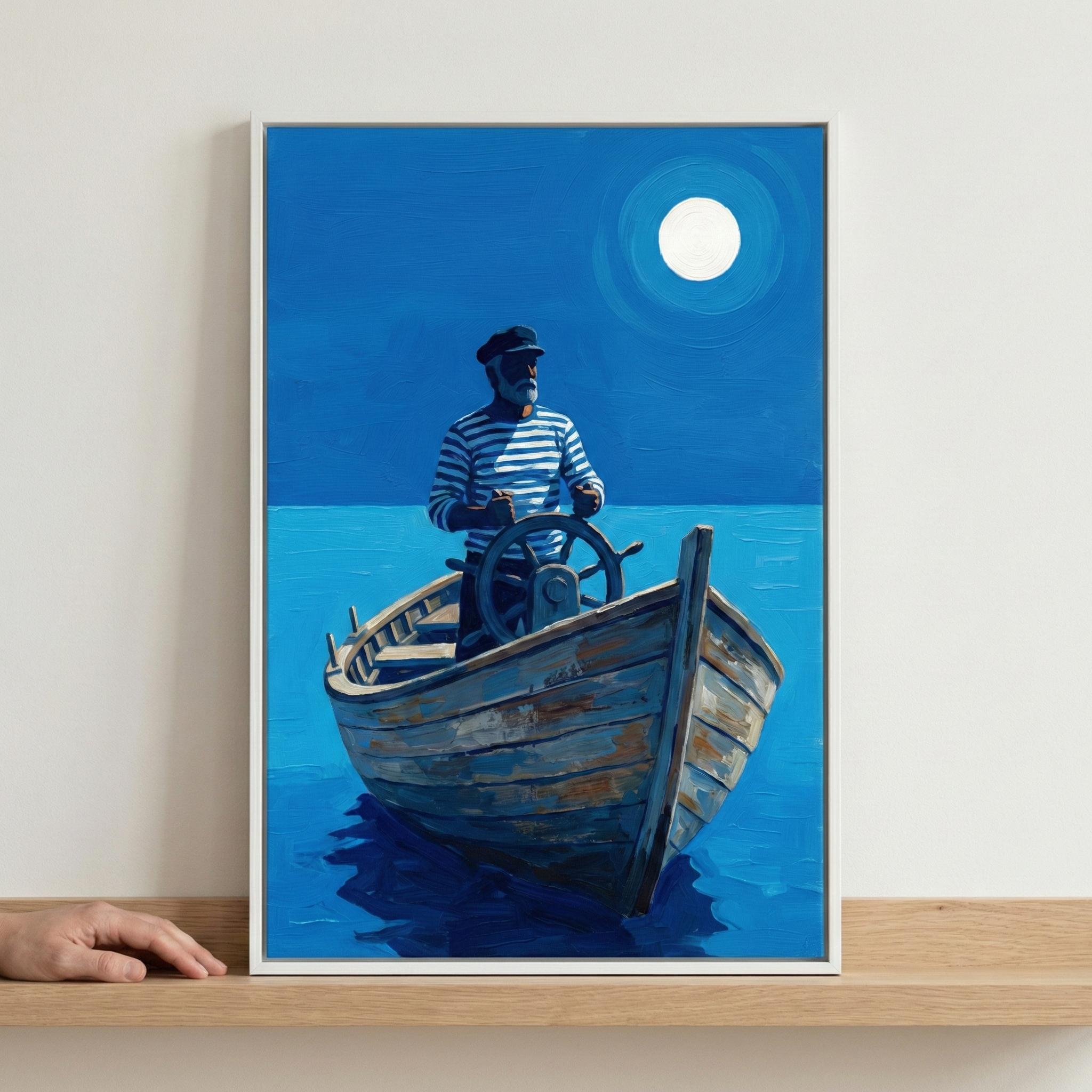 A vertical rectangular artwork in a white frame sits on a wooden shelf. The illustration depicts a bearded mariner wearing a dark captain's hat and a blue-and-white horizontal striped shirt, steering a weathered wooden boat. He stands behind a large steering wheel in the center of the craft. The boat sits on a calm expanse of blue water, which reflects a dark shadow beneath the vessel. 