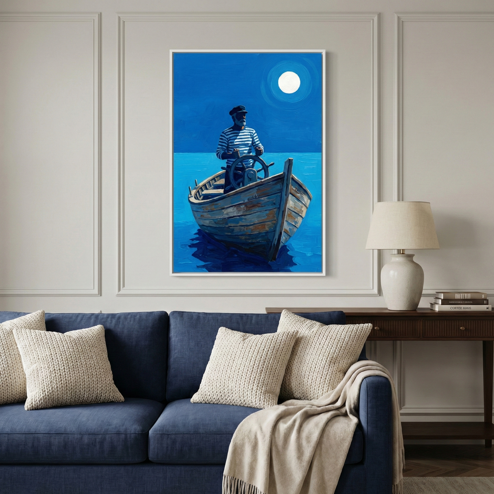This vertical framed artwork hangs as a central piece in a modern living room setting. The art piece illustrates a man in a blue and white striped shirt and a captain's hat steering a weathered wooden boat across a calm, deep blue sea. A large, luminous full moon glows in the dark blue night sky, casting a reflection on the water's surface. 
