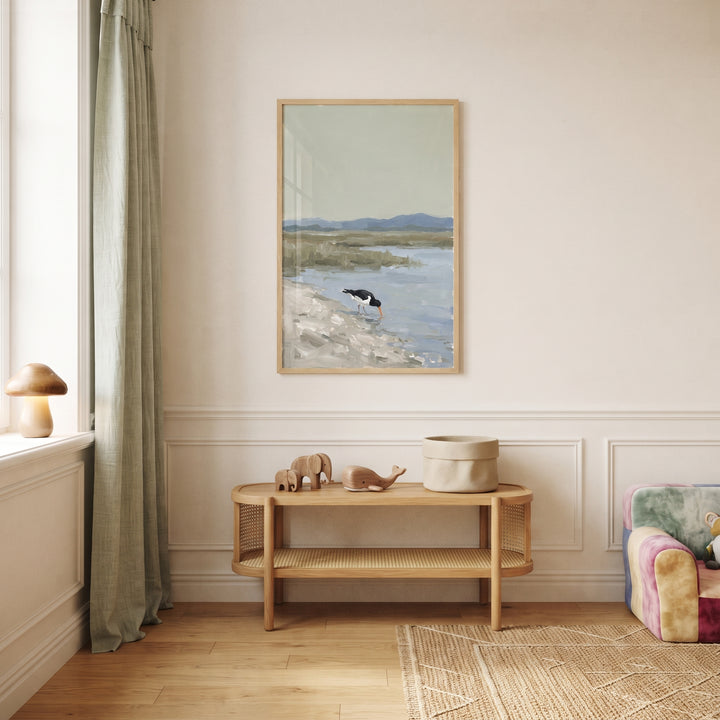 Orange beak oystercatcher bird wall art above a wooden bench with toys in a neutral room with a green curtain and rug.