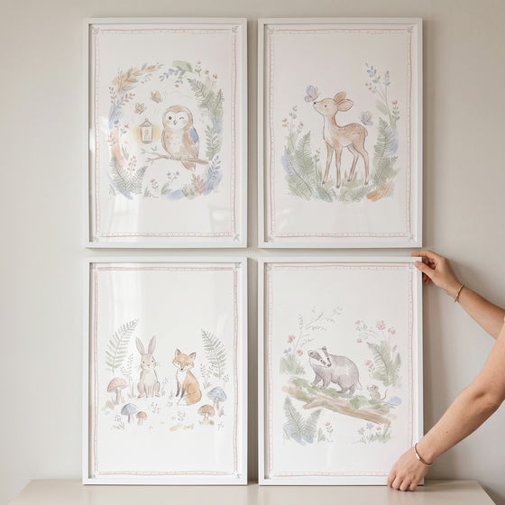 Four organic fern woodland animals wall art set of 4 prints featuring an owl, deer, rabbit, fox, and badger in white frames.