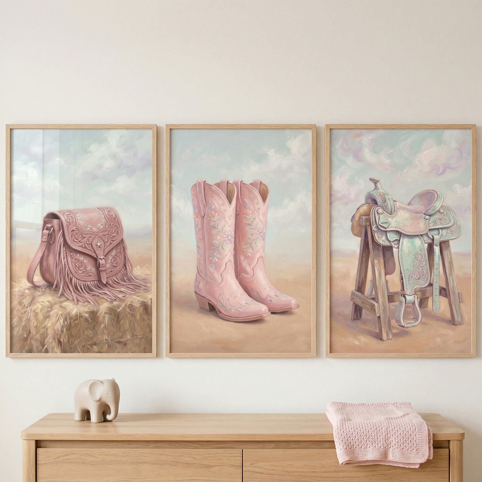 Ornate pink western gear wall art set of 3 with a fringed bag, boots, and saddle above a dresser with an elephant figurine.