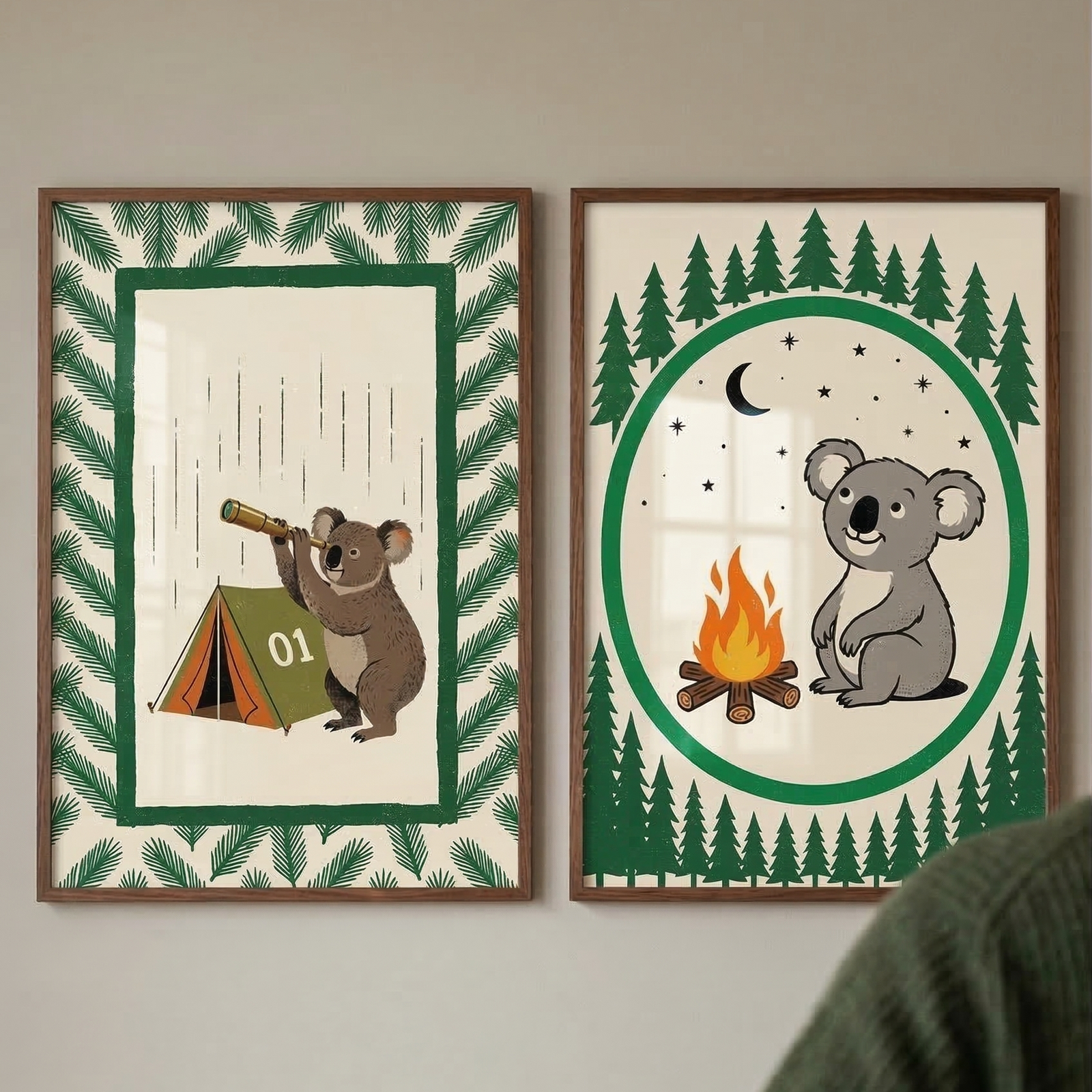 Two wooden-framed illustrations featuring a cartoon koala are displayed on a light wall. The left image shows a koala looking through a telescope next to a green tent with the number "01" on it, surrounded by a border of pine needles. The right image depicts the koala sitting by a campfire at night under a crescent moon and stars, framed by a circle and rows of pine trees. Both prints use a palette of green, brown, and cream tones. A person's shoulder is in the foreground.