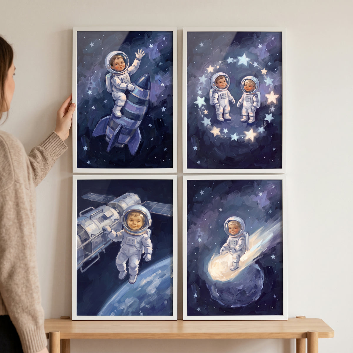 A person hangs a painterly blue baby astronaut wall art set of 4 featuring infants in space suits and celestial objects.