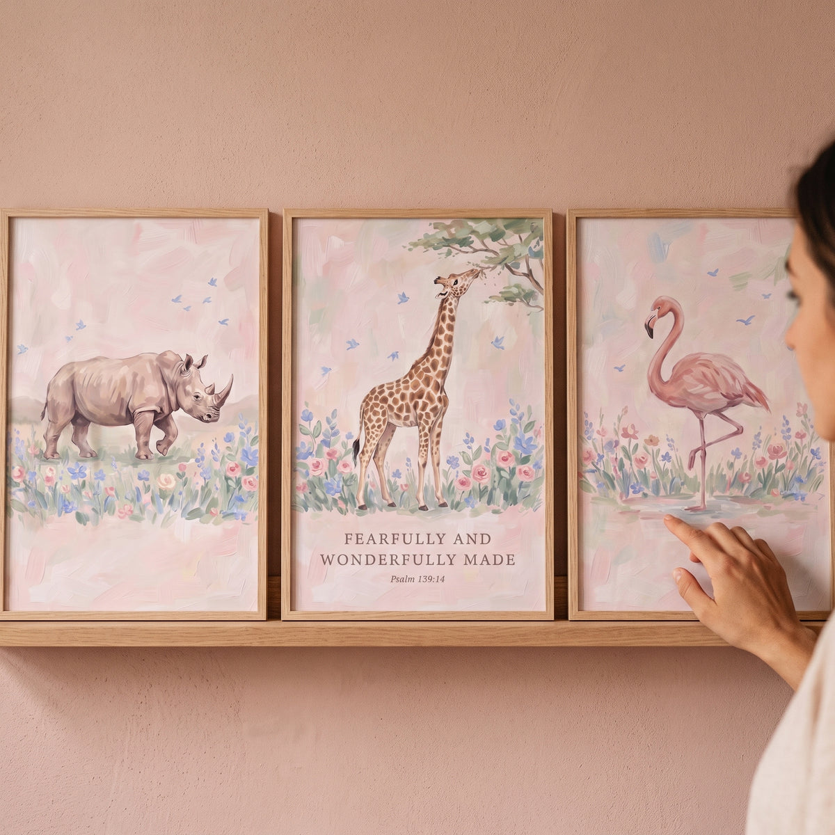 painterly blush safari animals wall art set of 3 featuring a rhino, giraffe, and flamingo with scripture on a shelf.