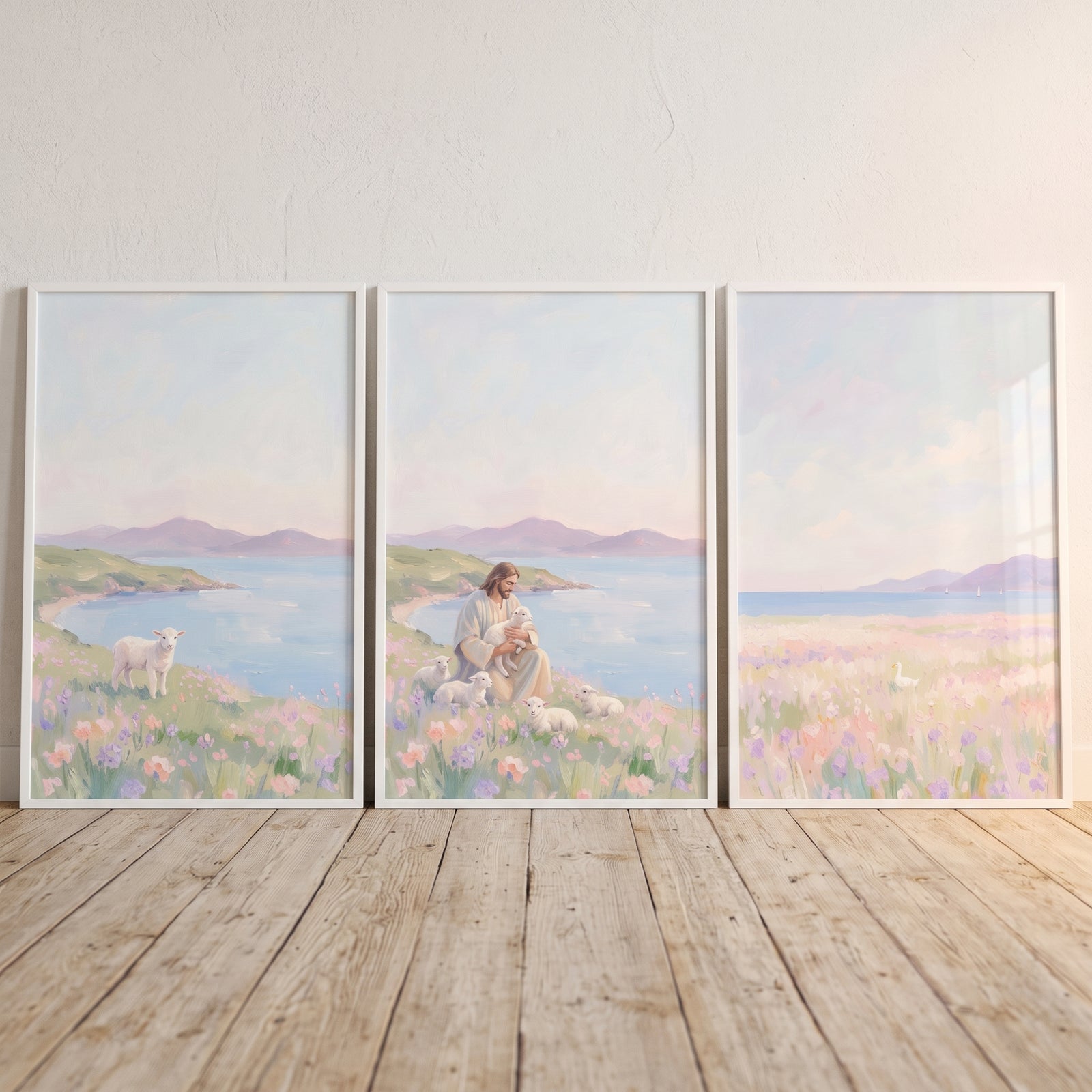 Jesus sits with lambs in a pale lilac coastal meadow wall art set of 3 on a light wood floor against a white wall.