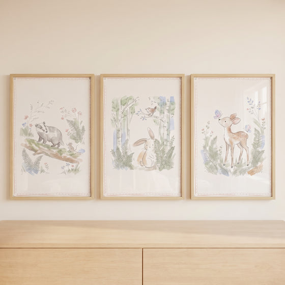 Pale watercolor woodland animal wall art set of 3 featuring a badger, rabbit, and deer above a wooden dresser.