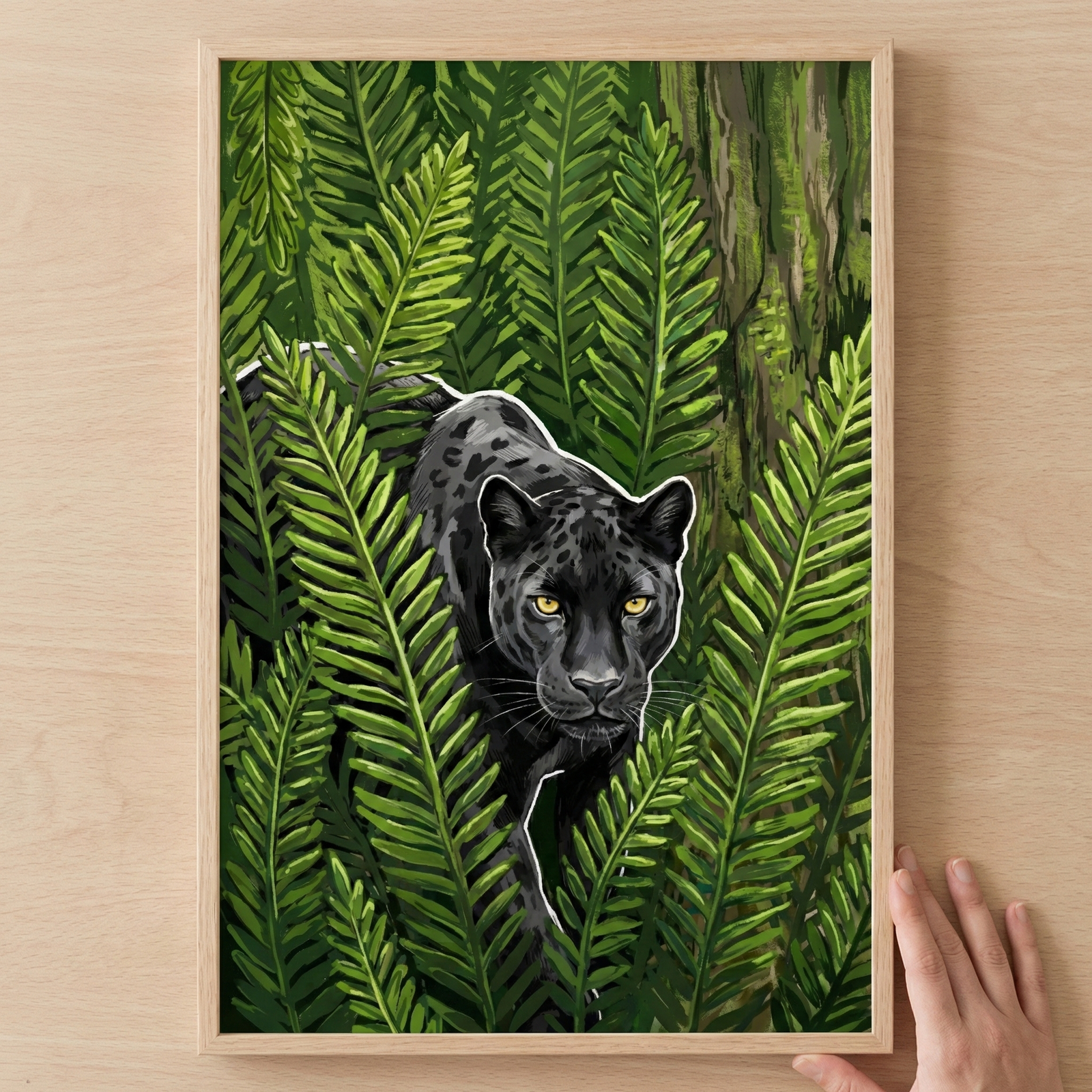 A stylized illustration of a black big cat with subtle spots and glowing golden eyes, peeking through a dense thicket of green fern fronds. The animal's form is accentuated with a thin white outline. The artwork is presented in a light wood frame, held by a hand against a wooden surface.