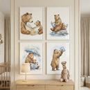 Four framed watercolor-style illustrations are displayed on a light-colored wall in a child's room. Each image features a large brown bear and a small cub reading books. They are shown reading together on the ground, sitting on a rock in water, huddled under an umbrella in the rain, and reaching for a book held high. Below the art, a wooden dresser holds a simple lamp and a tan crocheted rabbit. A wooden crib is partially visible to the left, framed by soft curtains.