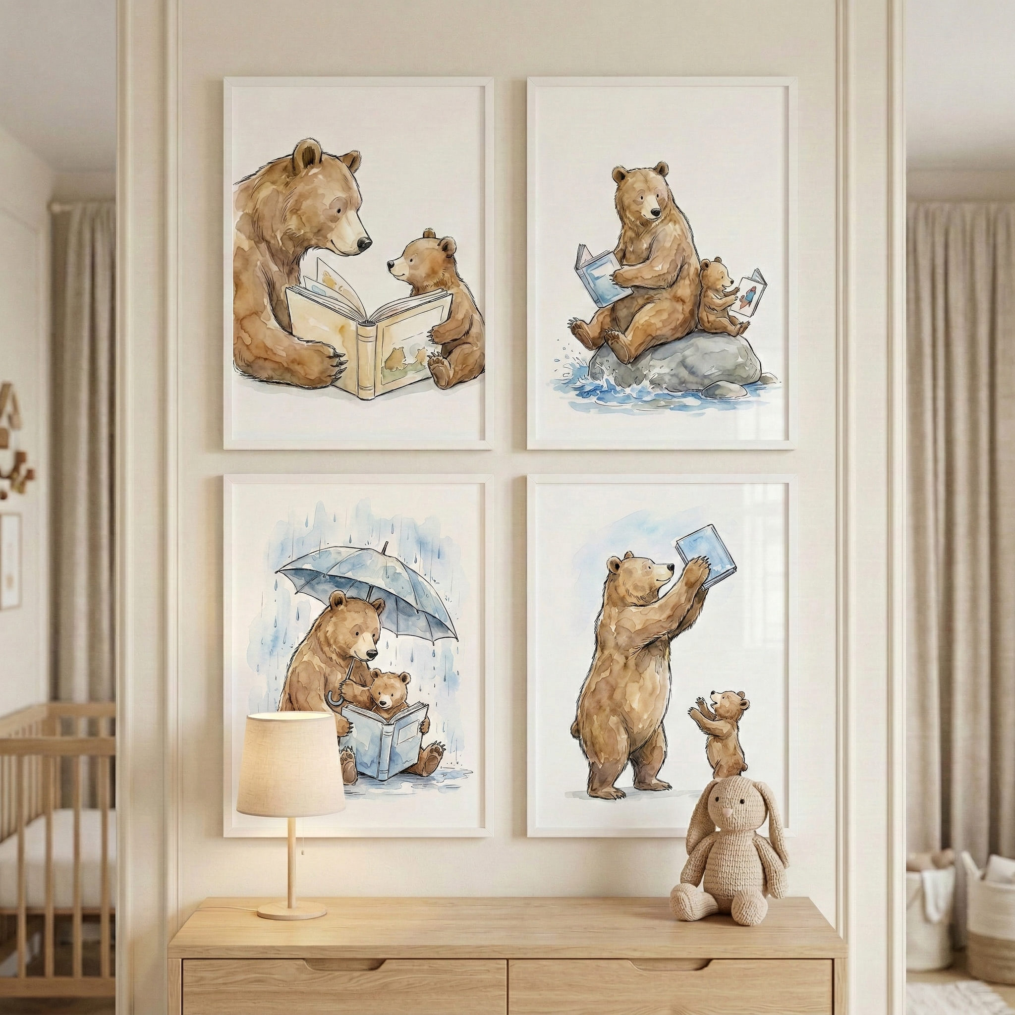 Four framed watercolor-style illustrations are displayed on a light-colored wall in a child's room. Each image features a large brown bear and a small cub reading books. They are shown reading together on the ground, sitting on a rock in water, huddled under an umbrella in the rain, and reaching for a book held high. Below the art, a wooden dresser holds a simple lamp and a tan crocheted rabbit. A wooden crib is partially visible to the left, framed by soft curtains.