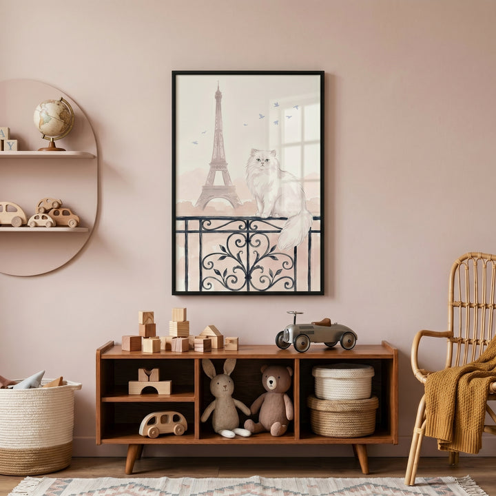 Paris balcony white cat wall art hangs above a wooden toy shelf in a pink nursery with a wicker chair and patterned rug.