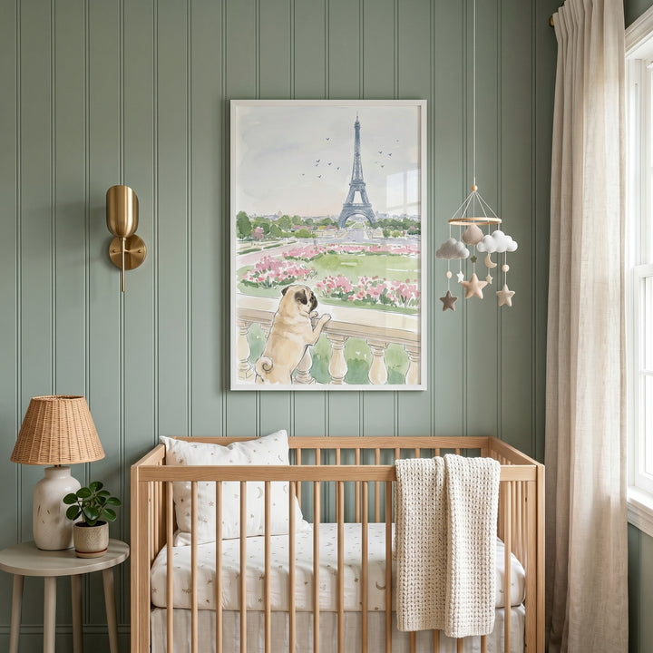 Nursery featuring paris sightseeing watercolor pug wall art above a light wood crib against green paneled walls.