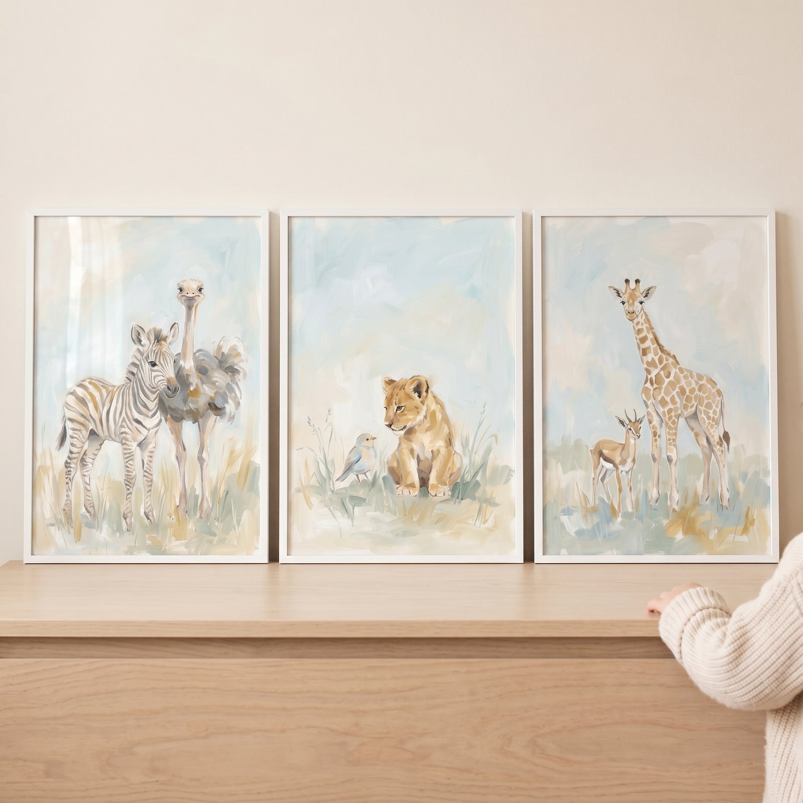 Pastel baby safari animals wall art set of 3 featuring a zebra, ostrich, lion cub, bird, giraffe, and gazelle on a shelf.