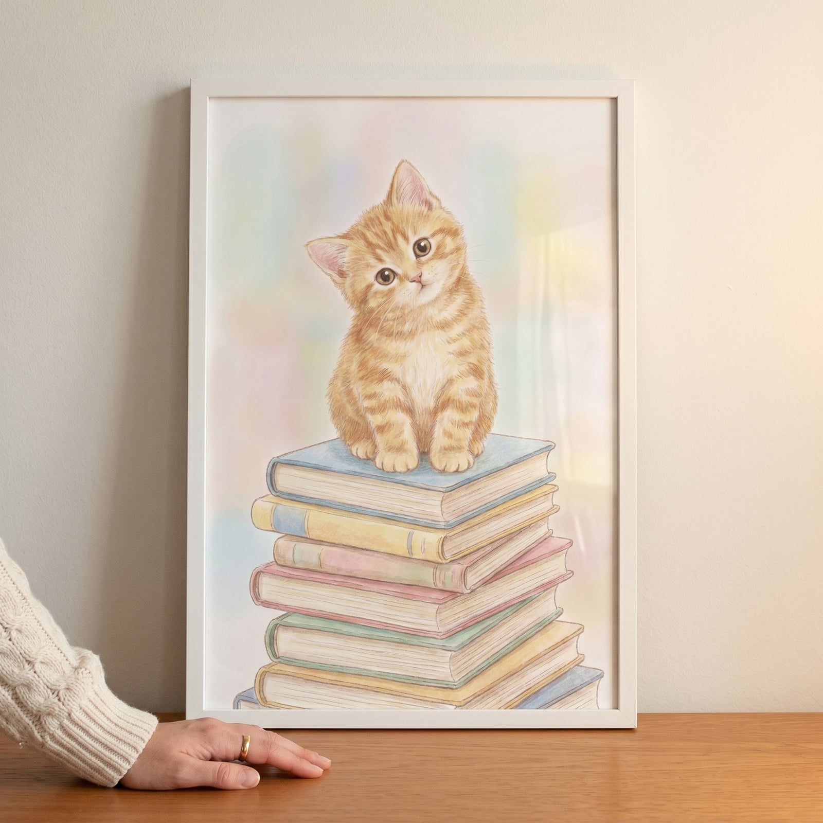 A ginger kitten sits on a colorful stack of books in this framed pastel book stack kitten wall art.