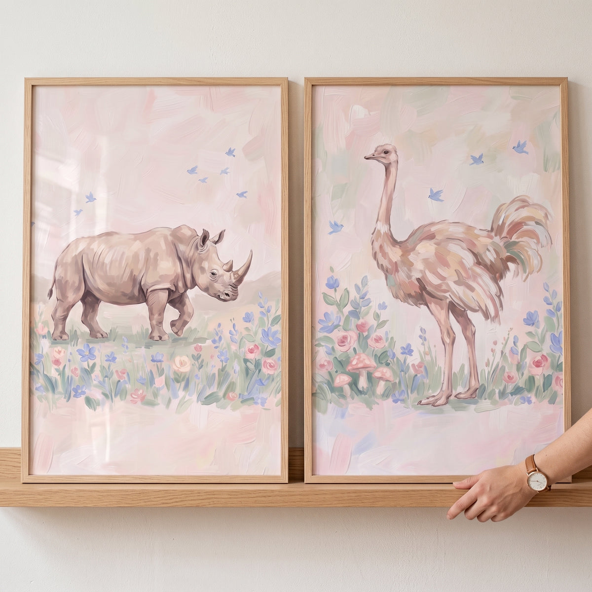 Rhino and ostrich in a pastel botanical safari animals wall art set of 2, framed on a shelf with a hand on the right.