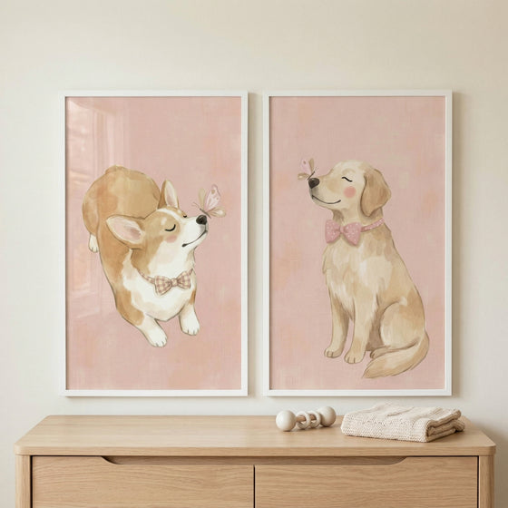 Two framed illustrations are displayed on a neutral-colored wall above a light wooden dresser. The dresser has two drawers and holds a small white wooden toy and a neatly folded cream-colored knit blanket. 
