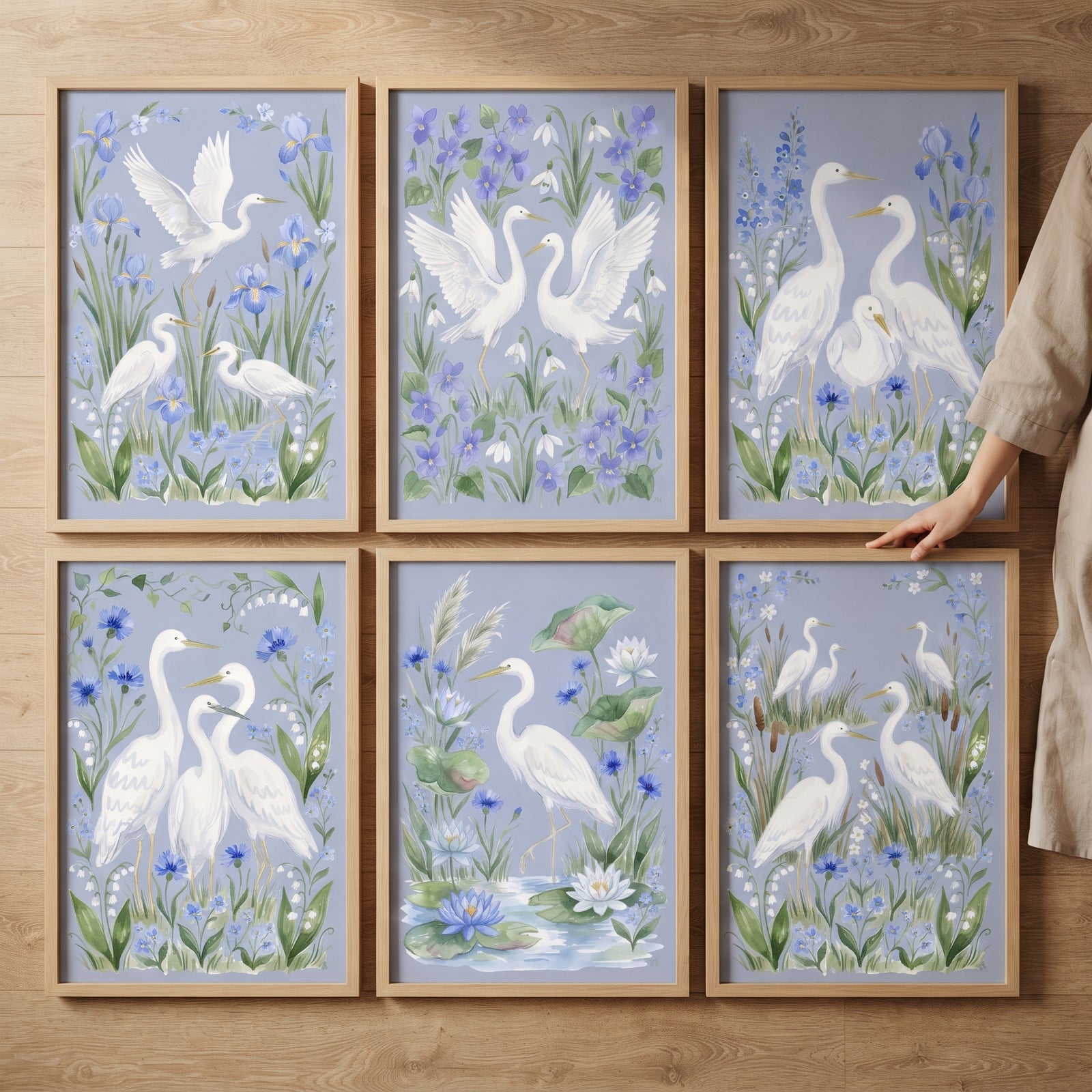 Six wood-framed prints form this pastel coastal wading bird wall art set of 6, featuring white herons and blue flowers.