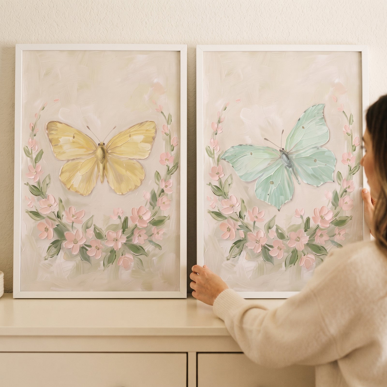 Pastel floral wreath butterfly wall art set of 2 with yellow and mint butterflies in white frames on a light dresser.