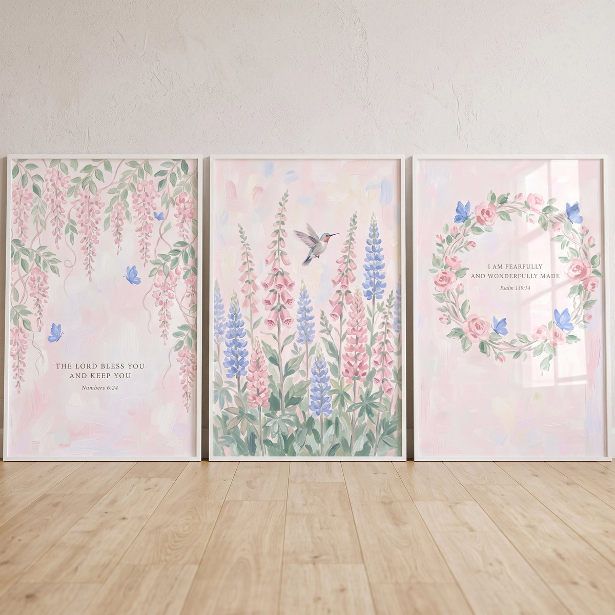 Pastel pink blue garden wall art set of 3 with flowers, butterflies, a hummingbird, and Bible verses in white frames.