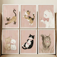 A set of six framed illustrations featuring various cats in a whimsical style, arranged in two rows of three. Each piece of artwork is enclosed in a simple white frame and set against a soft, pale pink background. Every cat in the series is adorned with a delicate pink bow. 