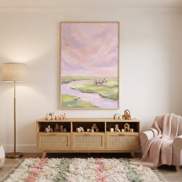 Pastel pink river rhino animal wall art hangs above a wooden console in a room with a shag rug and pink armchair.
