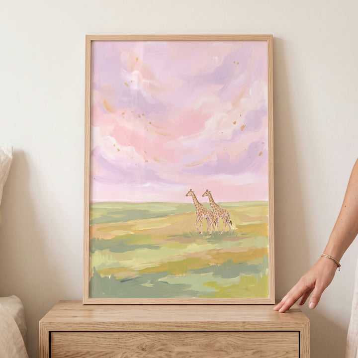 Framed pastel pink sunset giraffes animal wall art shows two giraffes in a field under a soft pink and purple sky.