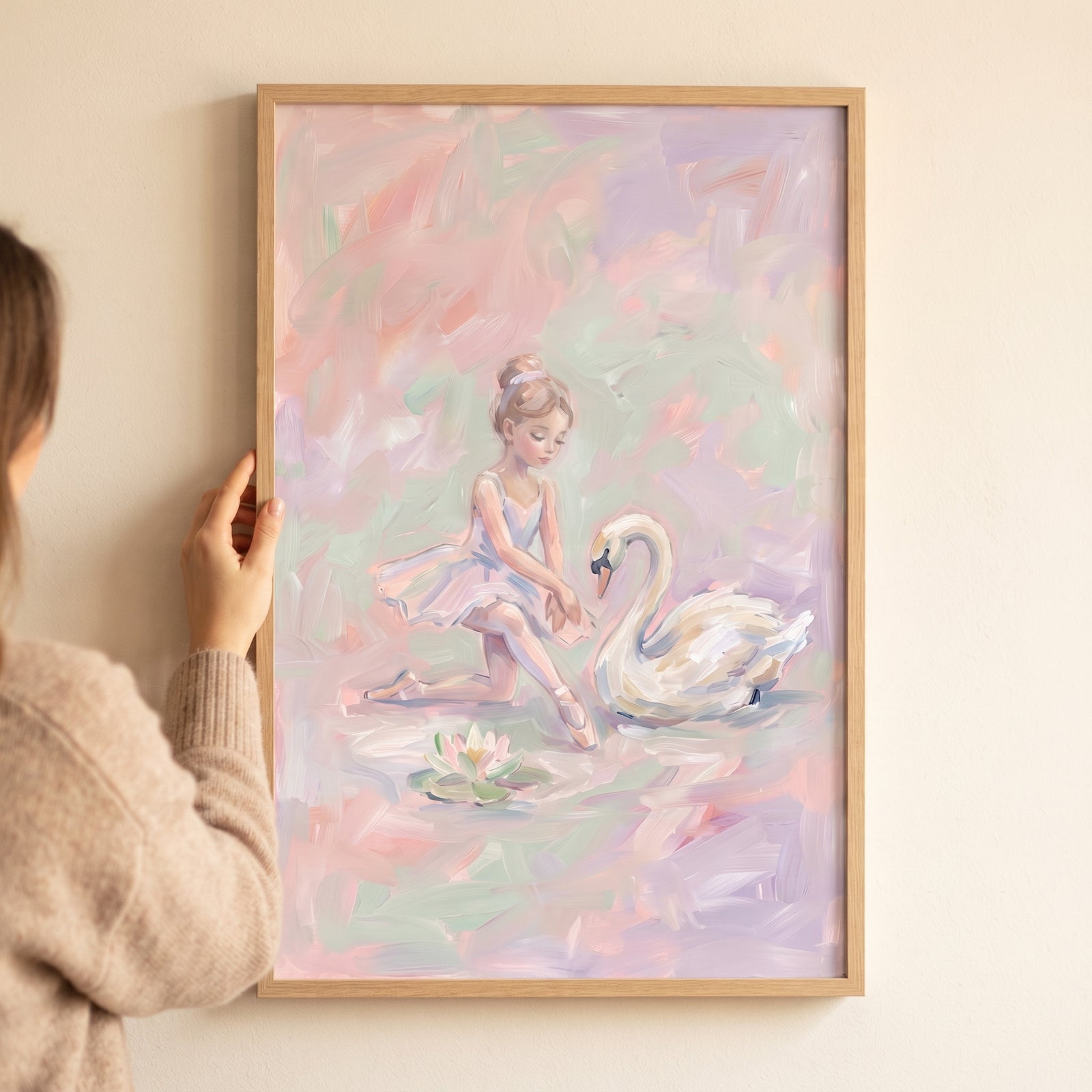 Framed pastel pink swan ballerina wall art with a girl in a tutu kneeling next to a white swan and a water lily.