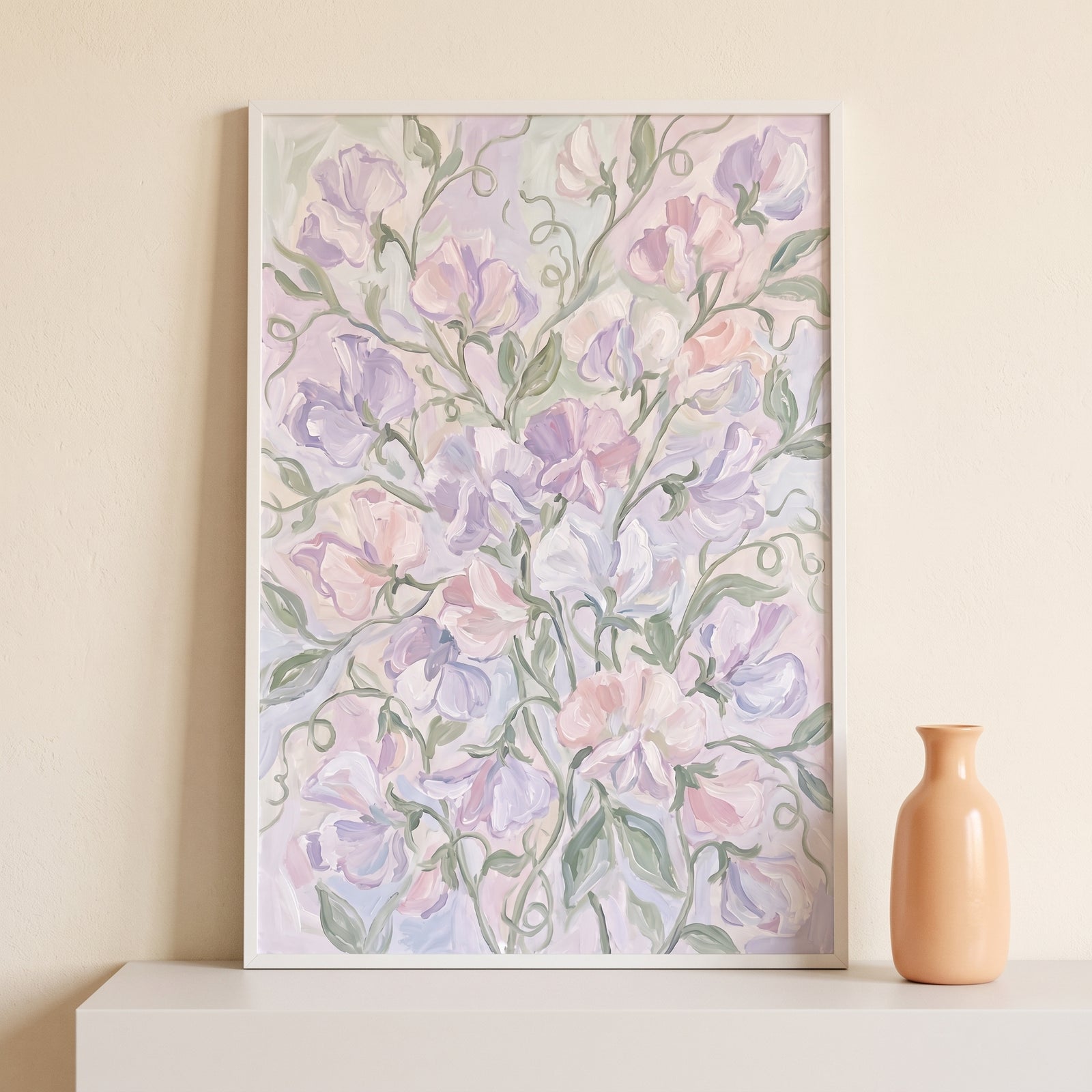 Pastel purple sweet pea floral wall art in a white frame sits on a ledge next to a small peach-colored vase.