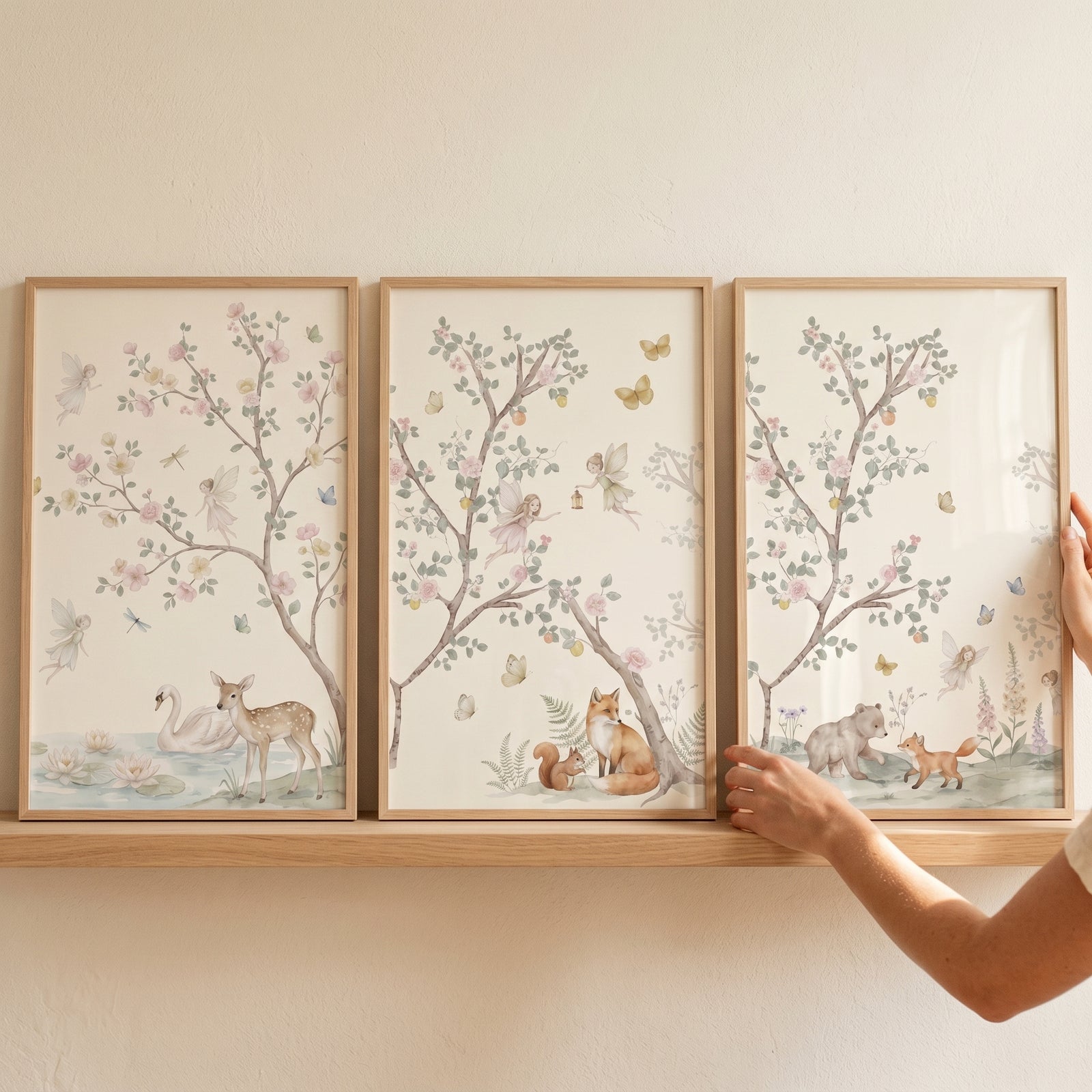 Pastel watercolor woodland fairies wall art set of 3 on a wooden shelf featuring a deer, swan, fox, and bear.