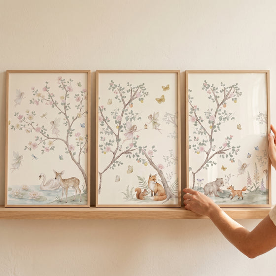 Pastel watercolor woodland fairies wall art set of 3 on a wooden shelf featuring a deer, swan, fox, and bear.