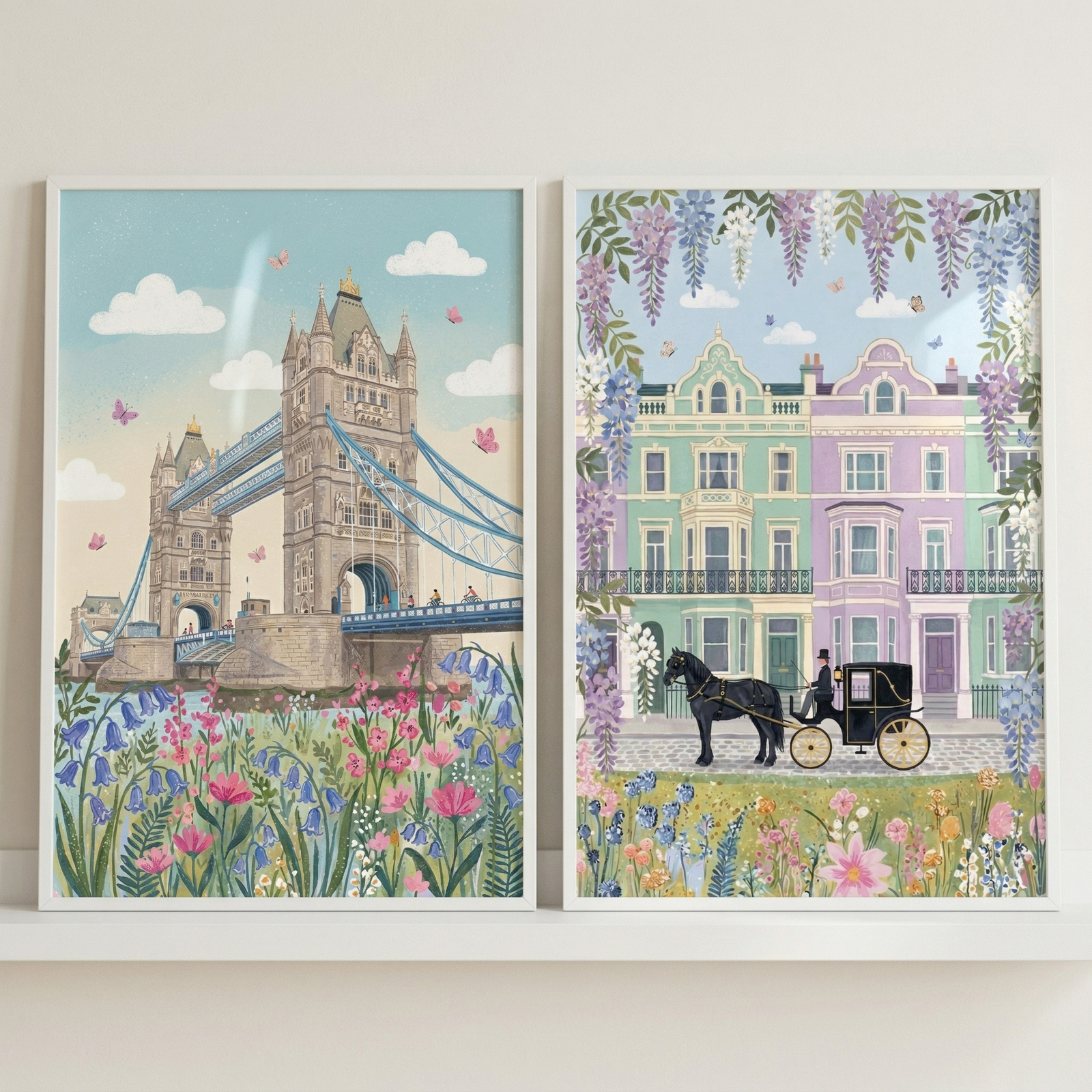 Two framed illustrations are displayed side-by-side on a white shelf. 

The illustration on the left depicts an ornate, historic stone bridge with two grand towers spanning across water. In the foreground, a vibrant cluster of pink and blue bellflowers grows along the riverbank. The pale blue sky is filled with soft, white clouds and several small pink butterflies.

