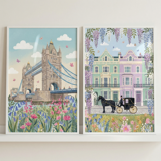 Two framed illustrations are displayed side-by-side on a white shelf. 

The illustration on the left depicts an ornate, historic stone bridge with two grand towers spanning across water. In the foreground, a vibrant cluster of pink and blue bellflowers grows along the riverbank. The pale blue sky is filled with soft, white clouds and several small pink butterflies.

