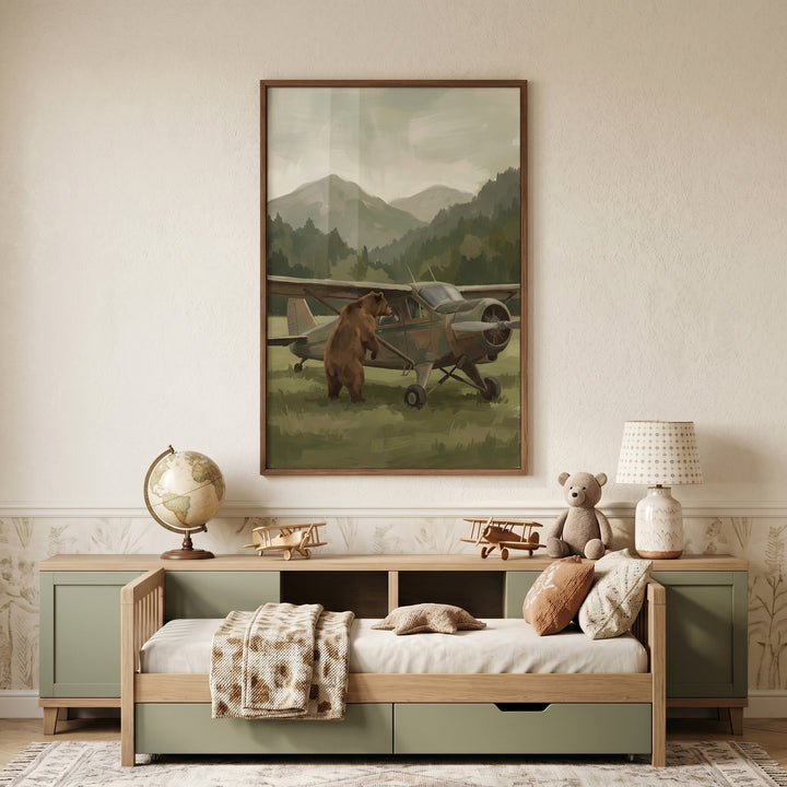 Peering into plane bear wall art hangs above a daybed in a room with wooden toy airplanes and a stuffed teddy bear.
