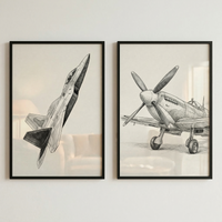 Two framed black and white sketches hang side-by-side on a neutral-colored wall. The sketch on the left features a sleek, modern jet fighter captured mid-flight from a dynamic, low-angle perspective. The drawing on the right depicts a classic, vintage propeller-driven aircraft resting on the ground, showcasing its large four-blade propeller and engine details. Both pieces are rendered in a realistic, hand-drawn style with fine lines and soft shading.