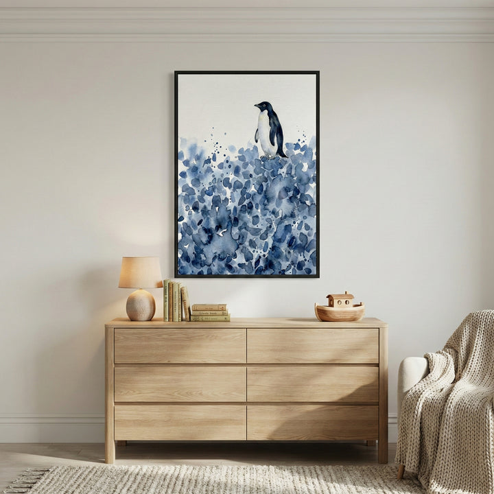 Framed watercolor giraffe art hanging on a white wall above a light wood dresser with a lamp and nursery toys.