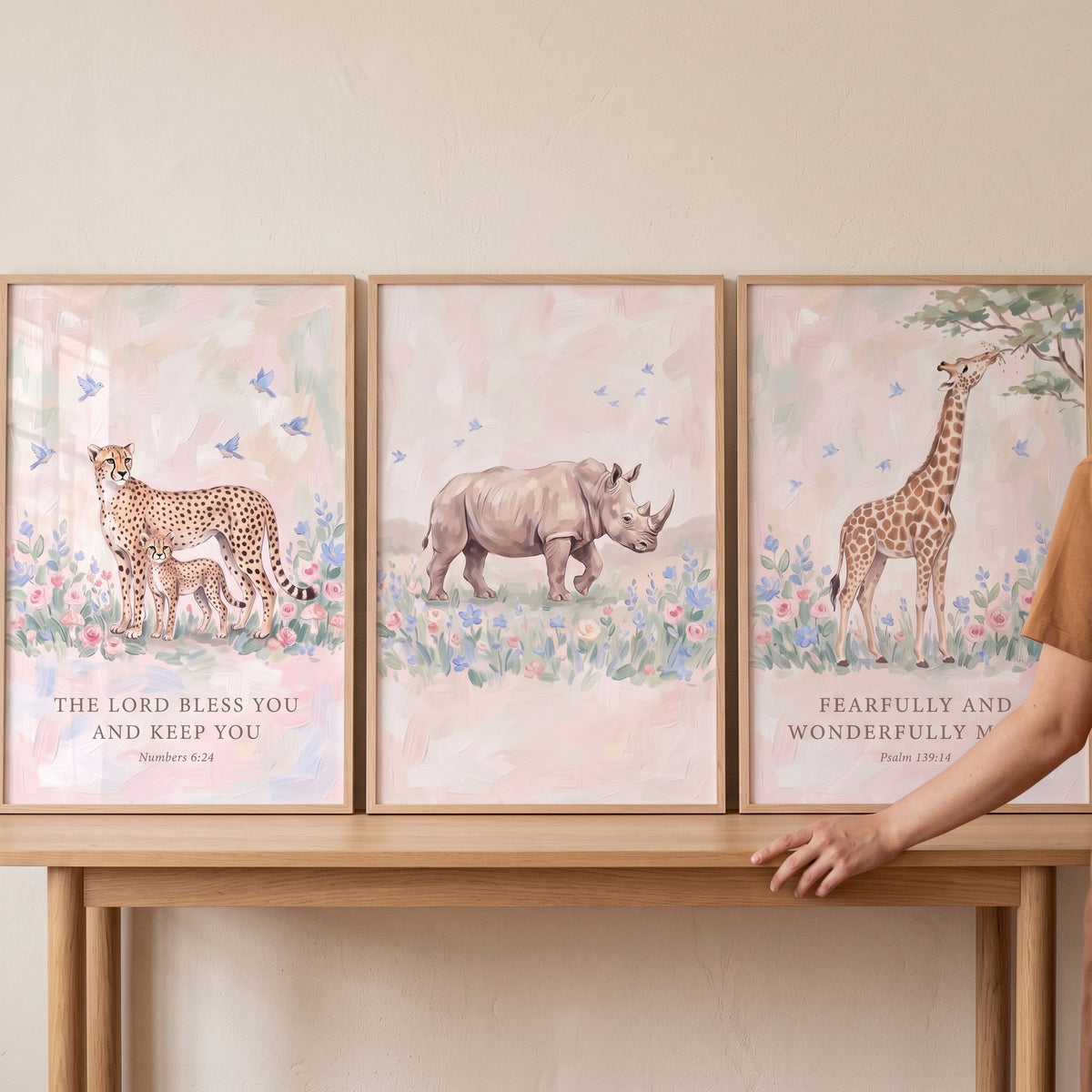 Petal pink savanna animals wall art set of 3 featuring a cheetah, rhino, and giraffe resting on a wooden table.