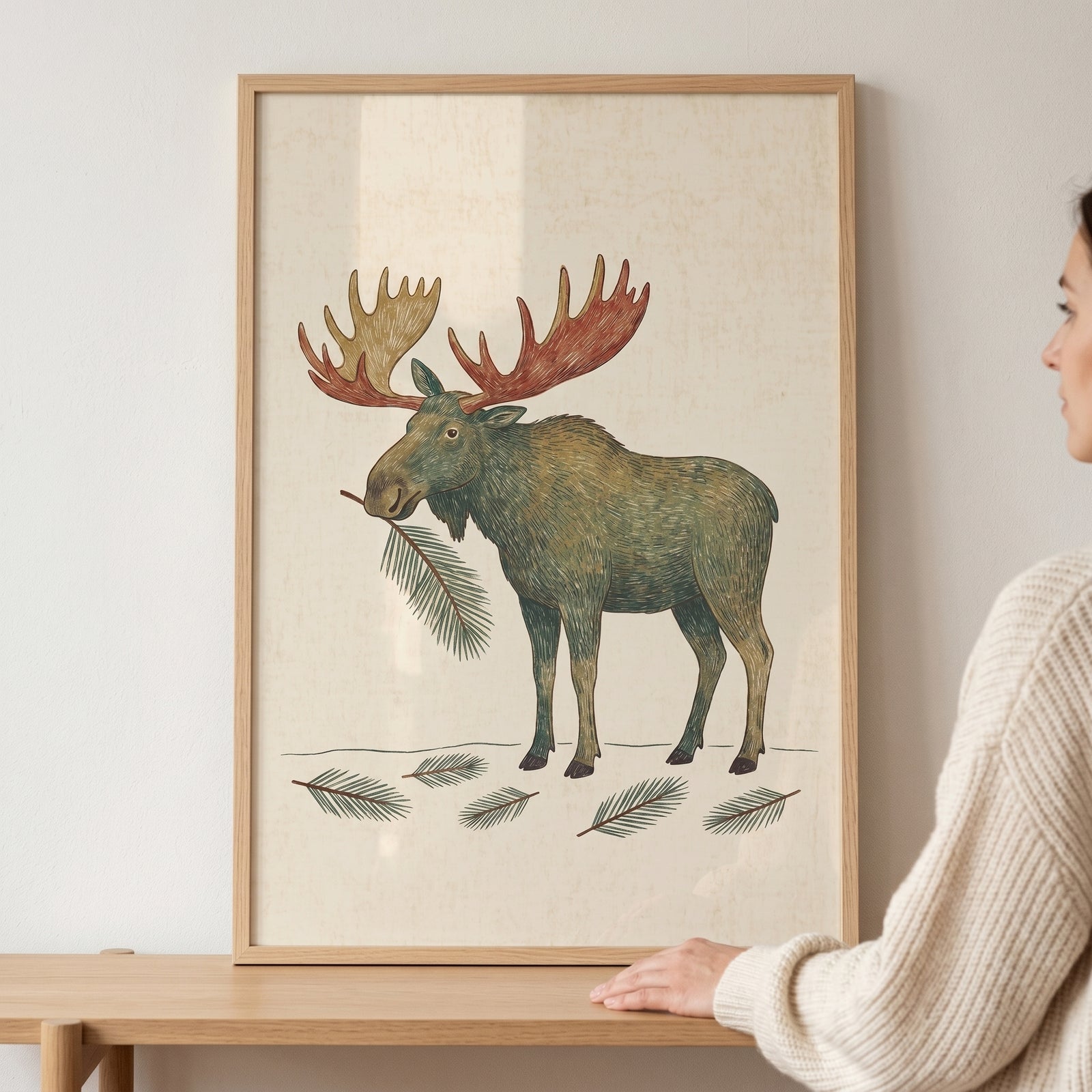 Framed pine branch mouth moose wall art featuring a moose with large antlers and fallen pine needles on cream paper.