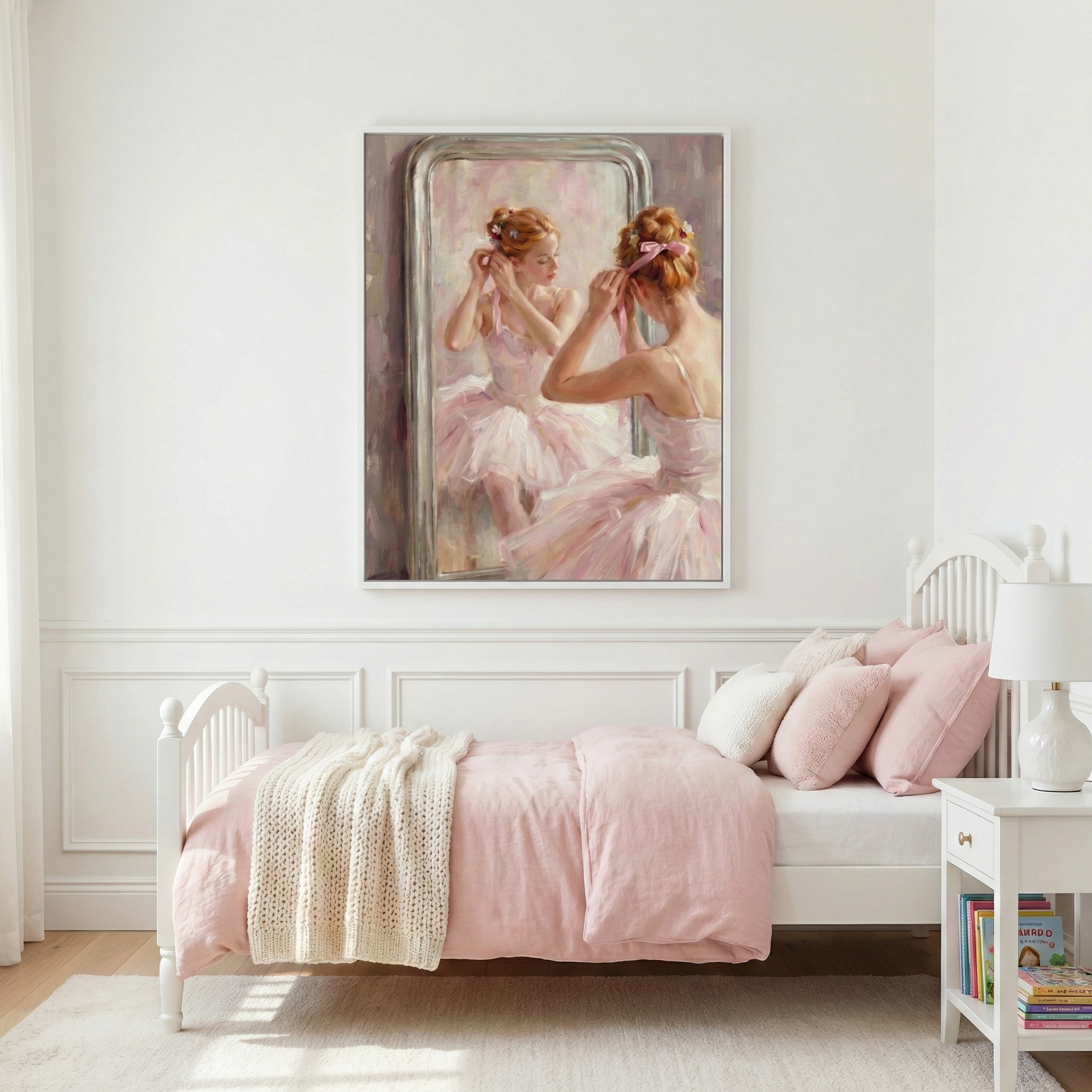 A bright child's bedroom features a white wooden bed with light pink linens and a cream-colored knit throw. Above the bed hangs a large piece of wall art depicting a ballerina in a pink tutu adjusting a ribbon in her hair while looking into a mirror. Beside the bed is a white nightstand with a textured lamp and several colorful books. The room has white paneled walls and a light rug, creating a soft, airy, and feminine atmosphere.
