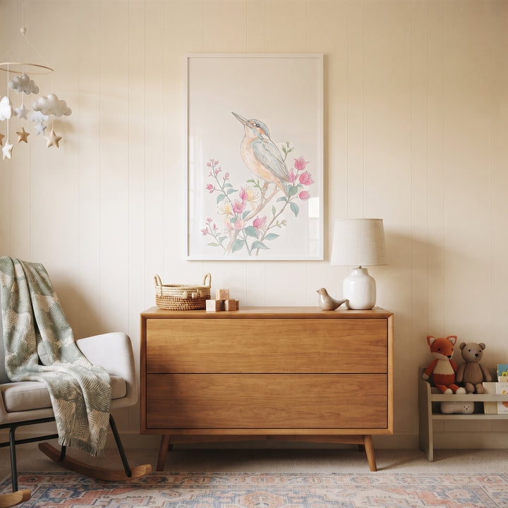 Nursery with a wooden dresser, rocking chair, and pink bloom floral kingfisher wall art on a neutral paneled wall.