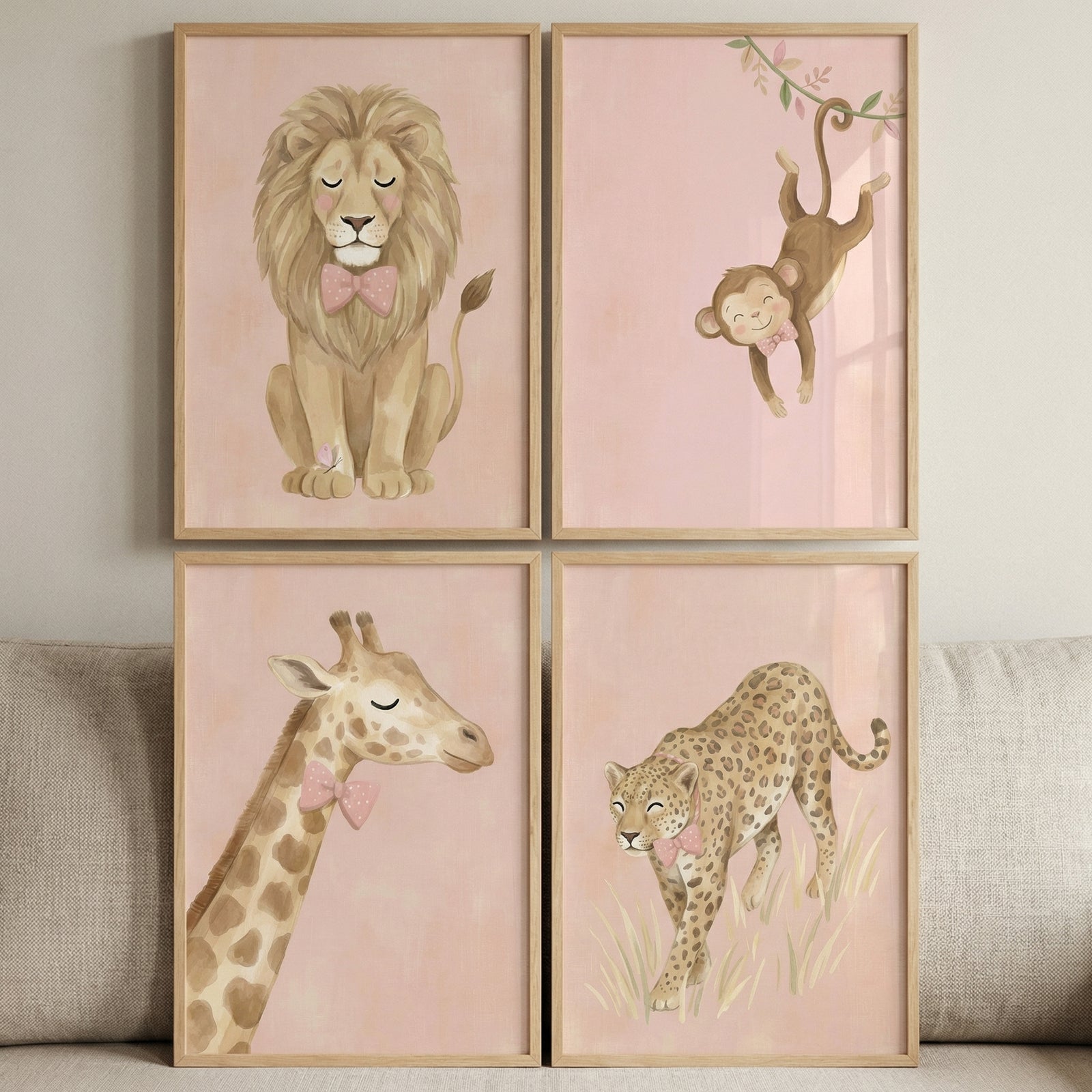 This image features a collection of four framed wall art pieces arranged in a two-by-two grid. Each rectangular frame is made of light-colored wood and contains a soft, illustrated depiction of a different zoo animal set against a pale pink, textured background.

