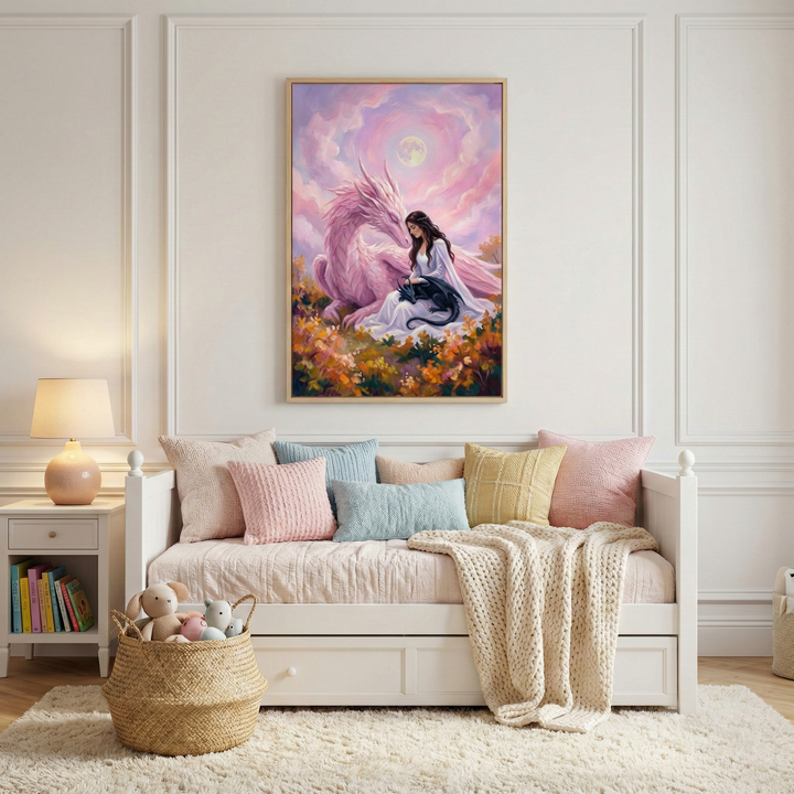 A serene white bedroom features a white daybed with a variety of pastel-toned textured pillows and a cream-colored knit throw. Above the bed, a large framed artwork depicts a woman in a white dress sitting in a field of flowers with a large pink dragon and a small dark one under a pastel moonlit sky. To the side, a white nightstand holds a lamp and books. A woven basket with stuffed toys sits on a plush white rug, all against a backdrop of classic wall paneling.