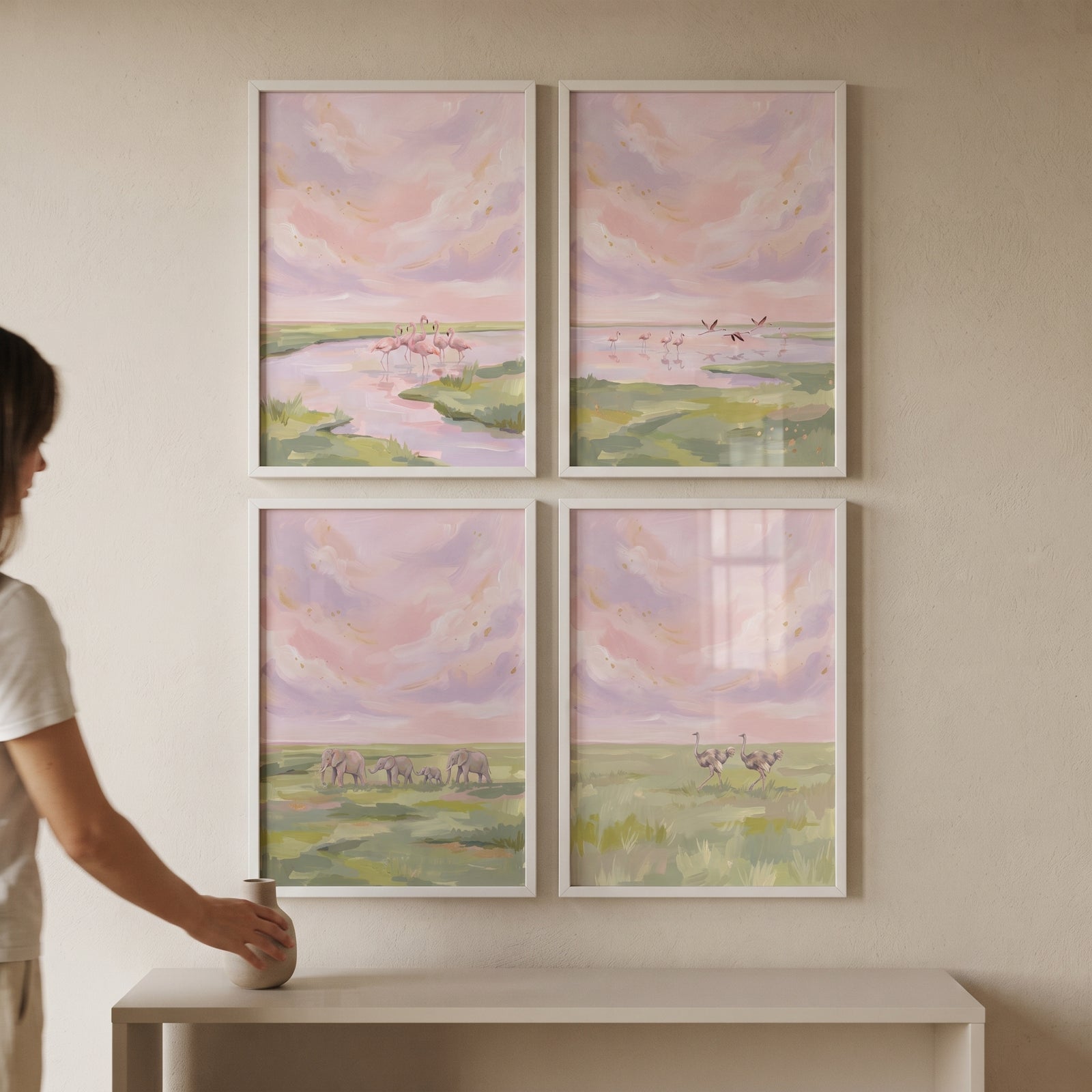 A woman places a vase near a pink dusk safari animals wall art set of 4 featuring flamingos, elephants, and ostriches.