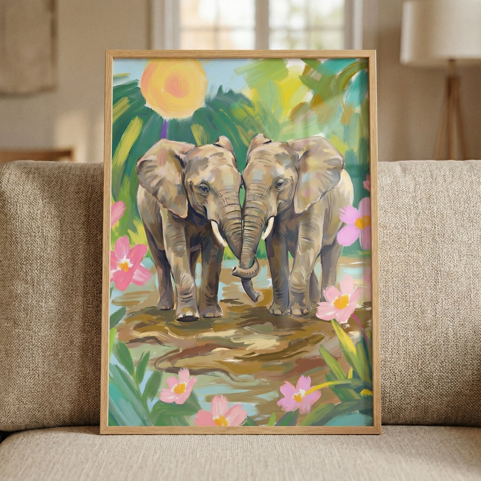 A framed piece of artwork depicting two elephants standing close together, their trunks gently intertwined. The scene is set in a lush, colorful environment filled with green foliage and oversized pink blossoms. In the background, a large, bright yellow sun glows against a variegated sky. 