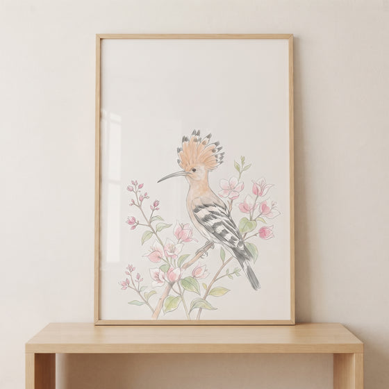 Pink floral crested hoopoe wall art in a light wood frame rests on a console table against a cream-colored wall.