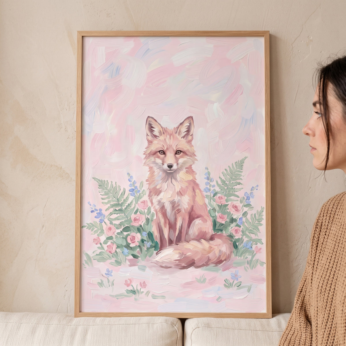 Pink floral sitting fox animal wall art in a light wood frame displayed on a neutral wall next to a person.